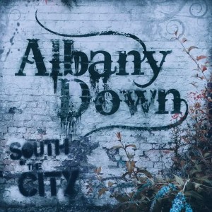 A painted brick wall with the paint wearing away and cracking off. Sprayed in the middle is the Albany Down wordmark and below it in the left corner is the title, South of the City